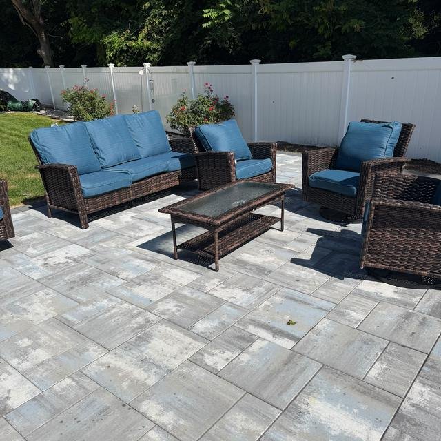 Wicker patio set with blue cushions on a paver patio