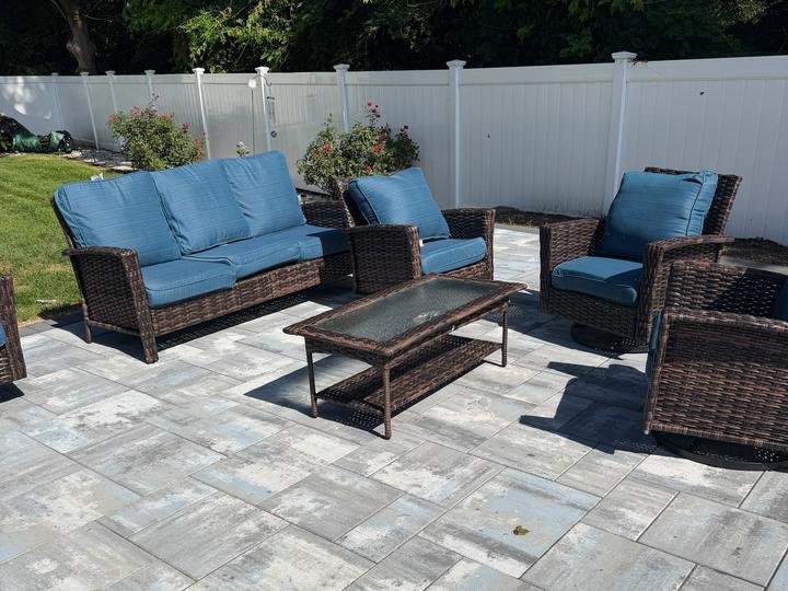 A wicker patio set with blue cushions assembled on a paver patio